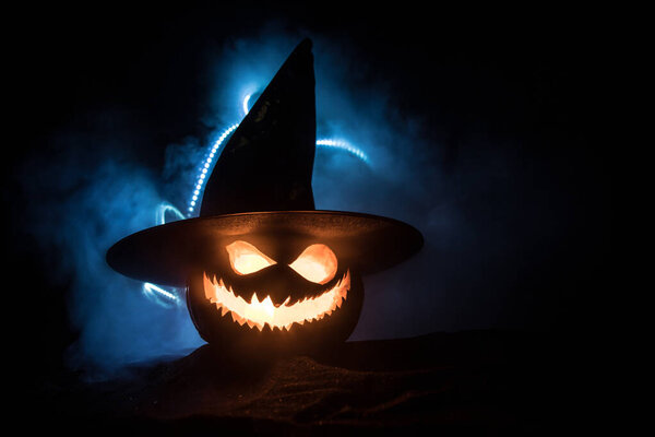 Halloween pumpkin smile and scary eyes for party night. Close up view of scary Halloween pumpkin with eyes glowing inside at black background.