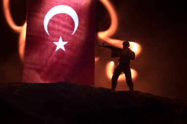 Türk ordusu konsepti. Türk bayrağına karşı silahlı asker silueti. Yaratıcı sanat dekorasyonu. Askeri siluetler dövüş sahnesinde sisli bir arka planda. Seçici odak
