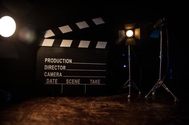 Film konsepti. Sis ve boşluk ile koyu tonlu arkaplanda minyatür film seti. Tripod ve klasördeki klasik kamera silueti. Seçici odak