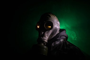 Çevre felaketi. Karanlık bir arka planda gaz maskeli kıyamet sonrası hayatta kalan biri. Gaz maskesi takan bir adamın dramatik portresi. Radyasyon koruması demek. Seçici odak