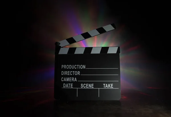 Movie concept. Miniature movie set on dark toned background with fog and empty space. Silhouette of clapboard on dark. Selective focus