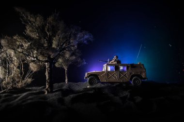 Savaş Konsepti. Savaş sahnesi sisli gökyüzü arka planında geceleri Bulutlu Skyline 'ın altında siluetlerle savaşmak. Askerlerin sanat eserleriyle donatılmış askeri araç. Seçici odak