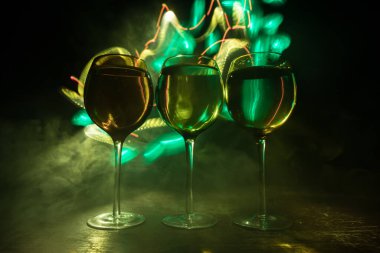 Ahşap masada şarap kadehi ve arka planda güzel renkli ışıklar. Karanlık arka planda şarap kadehleri. Seçici odaklanma. Kulüp içki konsepti