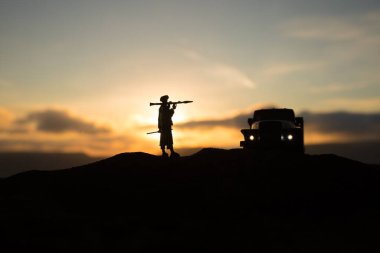 Askeri askerler bazuka ve roketatarlı siluetler. Savaş Konsepti. Askeri siluetler savaş sahnesinde sisli gökyüzü arka planında, gün batımında RPG ile Mojahed.