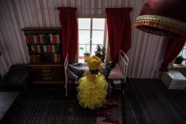 Geceleri mobilyaları ve pencereleri olan gerçekçi bir bebek odası. Pencerede oturan romantik bir çift. Kadın ve erkek yatak odasında sevişiyor. Sanat eseri masa dekorasyonu. Seçici odak.