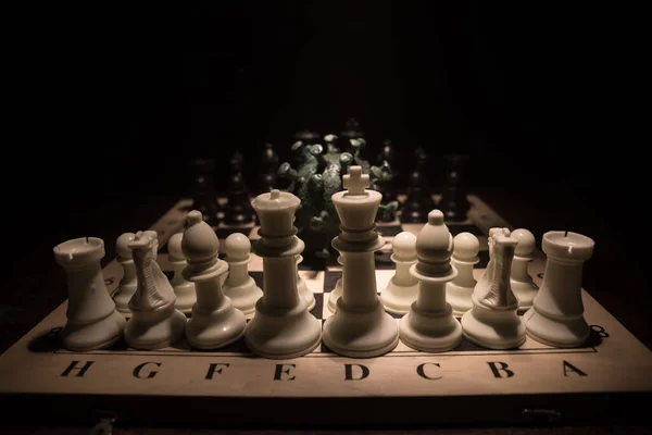 Chess board game concept strategy of business in Covid global pandemic. Big Corona virus miniature model on chessboard with fog and backlight. Creative artwork decoration. Selective focus