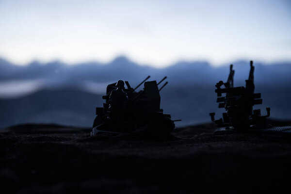 Силуэт зенитной пушки на поле боя во время захода солнца. Диорама стола для творческих работ. Выборочный фокус. , Силуэты солдат мировой войны под облачным горизонтом на закате
.