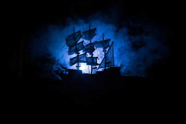 Black silhouette of the pirate ship in night. night scene of ghost pirate ship in the sea with mysterious light. Selective focus
