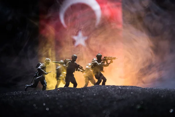 Turkish army concept. Silhouette of armed soldiers against a Turkish flag. Creative artwork decoration. Military silhouettes fighting scene dark toned foggy background. Selective focus