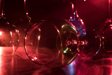 Ahşap masada şarap kadehi ve arka planda güzel renkli ışıklar. Karanlık arka planda şarap kadehleri. Seçici odaklanma. Kulüp içki konsepti