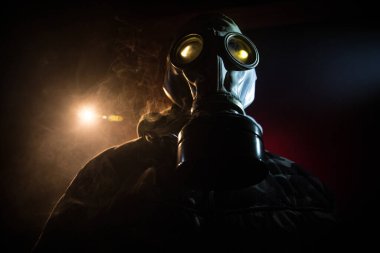 Çevre felaketi. Karanlık bir arka planda gaz maskeli kıyamet sonrası hayatta kalan biri. Gaz maskesi takan bir adamın dramatik portresi. Radyasyon koruması demek. Seçici odak