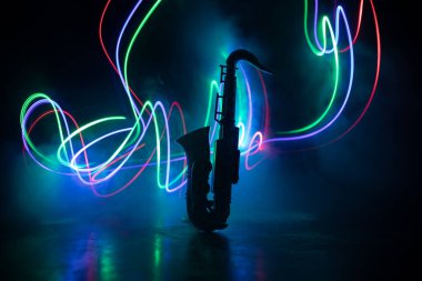Music concept. Saxophone jazz instrument. Alto gold sax miniature with colorful toned light on foggy background. Saxophone music instrument in lowlight. Selective focus clipart