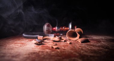 Shisha konsepti. Tahta masada kırık shisha kasesi. Işıklı karanlık bir atmosfer. Seçici odak.