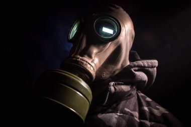 Çevre felaketi. Karanlık bir arka planda gaz maskeli kıyamet sonrası hayatta kalan biri. Gaz maskesi takan bir adamın dramatik portresi. Radyasyon koruması demek. Seçici odak