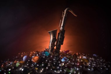 Müzik konsepti. Saksafon caz enstrümanı. Alto altın saksafon minyatürü, sisli arka planda renkli ışık. Düşük ışıkta saksafon müzik aleti. Seçici odak