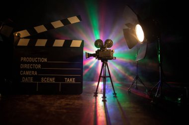 Film konsepti. Sis ve boşluk ile koyu tonlu arkaplanda minyatür film seti. Tripod ve klasördeki klasik kamera silueti. Seçici odak
