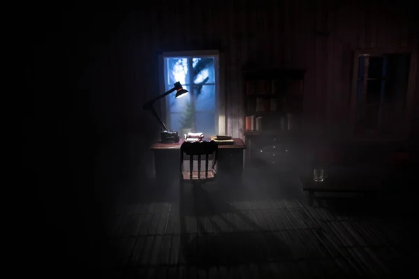夜には家具や窓のあるリアルな人形の家のリビングルーム 男は暗い部屋のテーブルの上に座っている 世界的なウイルスのパンデミックの間に家にいるという概念 選択的焦点 — ストック写真