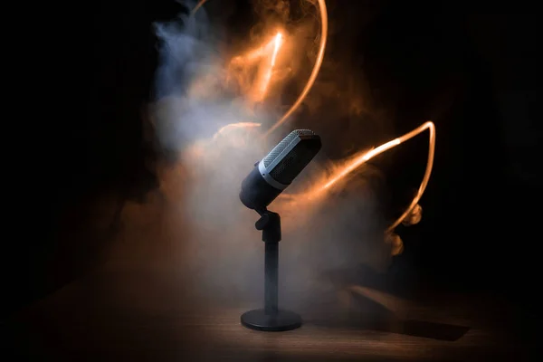 Microphone for sound, music, karaoke in audio studio or stage. Mic technology. Speech broadcast equipment. Microphone in dark room on table with backlight. Selective focus