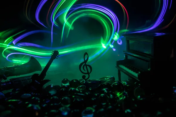 Music concept. Musical symbol treble clef stainless steel miniature with colorful toned light on foggy background. Musical instruments in lowlight. Selective focus