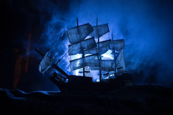 Black silhouette of the pirate ship in night. night scene of ghost pirate ship in the sea with mysterious light. Selective focus