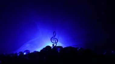 Müzik konsepti. Müzikal sembol, anahtarsız paslanmaz çelik minyatür sisli arka planda renkli bir ışık. Loş ışıkta müzik aletleri. Seçici odak