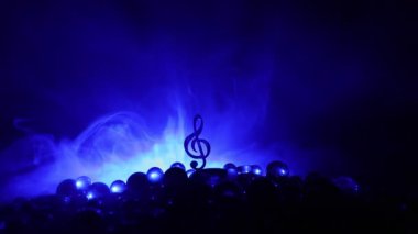 Müzik konsepti. Müzikal sembol, anahtarsız paslanmaz çelik minyatür sisli arka planda renkli bir ışık. Loş ışıkta müzik aletleri. Seçici odak