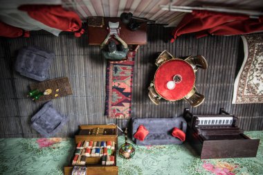 Geceleri mobilyası ve penceresi olan gerçekçi bir bebek evi oturma odası. Karanlık odada masada oturan bir adam. Küresel virüs salgını sırasında evde kalma kavramı. Seçici odak.