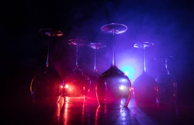 Ahşap masada şarap kadehi ve arka planda güzel renkli ışıklar. Karanlık arka planda şarap kadehleri. Seçici odaklanma. Kulüp içki konsepti