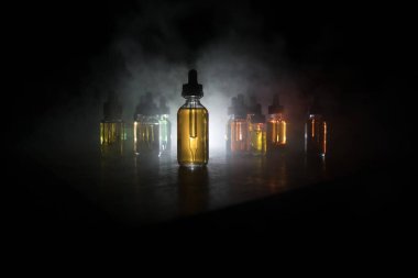 Vape konsepti. Karanlık arka planda duman bulutları ve tüp sıvısı şişeleri. Işık efektleri. Arka plan, vape reklamı ya da vape arkaplan olarak kullanışlı. Seçici odak