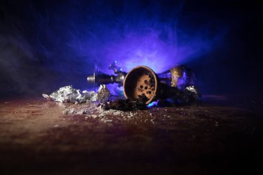 Shisha konsepti. Masada shisha hazırlıyorum. Ahşap masada kullanılmış shisha kasesi. Işıklı karanlık bir atmosfer. Seçici odak.