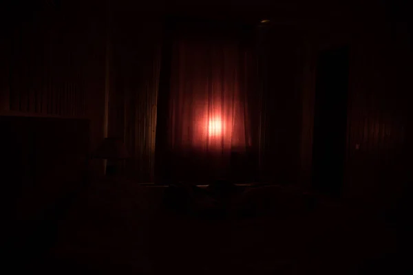 Light in window with curtain inside bedroom at night. Horror scene. Halloween concept. Blurred silhouette of ghost