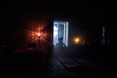 Geceleri mobilyası ve penceresi olan gerçekçi bir bebek evi oturma odası. Pencerede oturan romantik bir çift. El yapımı gerçekçi bebek eviyle sanat masası dekorasyonu. Seçici odak.