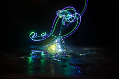 İçki, kırık cam konsepti. Ahşap masada kırık bardaklar, sisli, koyu tonlu arka plan. Seçici odak