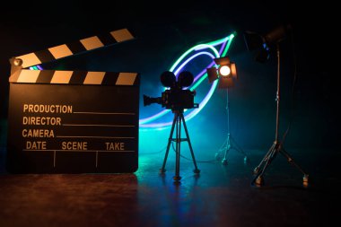 Film konsepti. Sis ve boşluk ile koyu tonlu arkaplanda minyatür film seti. Tripod ve klasördeki klasik kamera silueti. Seçici odak