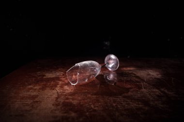 İçki, kırık cam konsepti. Koyu tonlu, sisli, ahşap masadaki kırık camlar. Seçici odak