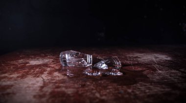 İçki, kırık cam konsepti. Koyu tonlu, sisli, ahşap masadaki kırık camlar. Seçici odak