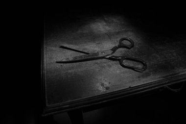 Düşük ışıkta eski terzi makası ahşap masada. Renkli sisli arka ışıklandırmalı sanat dekorasyonu. Seçici odak