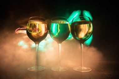 Ahşap masada şarap kadehi ve arka planda güzel renkli ışıklar. Karanlık arka planda şarap kadehleri. Seçici odaklanma. Kulüp içki konsepti