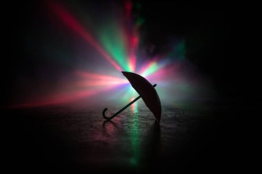 Masanın üzerinde koyu tonlu sisli minyatür bir şemsiye silueti var. Yaratıcı bir kavram. Seçici odak