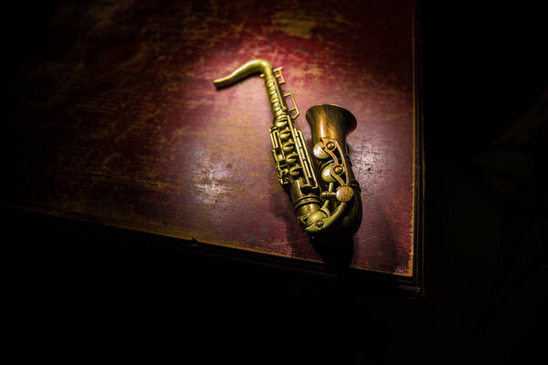 Music concept. Saxophone jazz instrument. Alto gold sax miniature with colorful toned light on foggy background. Saxophone music instrument in lowlight. Selective focus