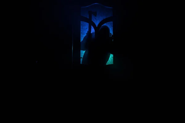 透过关闭的玻璃门 描绘了门上一个未知影子的轮廓 带着烟熏背景的夜间恐怖的侧影女孩 — 图库照片