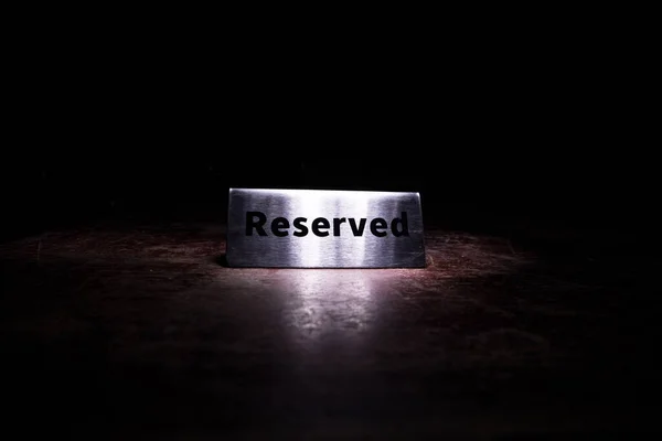 テーブルの上に予約記号 木のテーブルの上に予約のタグ 暗闇の中で予約と金属タグ レストランで予約されたテーブル カラフルなライトで創造的なコンセプト 選択的焦点 — ストック写真