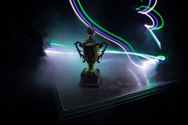 Altın kupa masa arkasında fotokopi alanı olan bir kupa. Renkli sisli arka ışıklandırmalı yaratıcı sanat dekorasyonu. Seçici odak