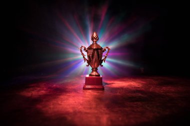 Altın kupa masa arkasında fotokopi alanı olan bir kupa. Renkli sisli arka ışıklandırmalı yaratıcı sanat dekorasyonu. Seçici odak