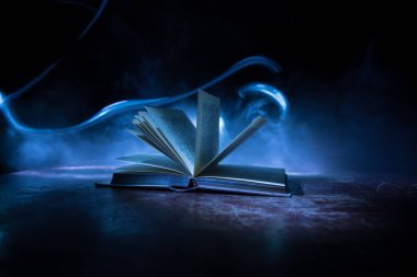 Bir yığın eski kitap. Ahşap masanın üzerinde antika bir kitap. Karanlıkta parlayan bir kitabın etrafında sihirli bir yıldırım. Seçici odak