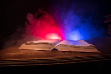 Bir yığın eski kitap. Ahşap masanın üzerinde antika bir kitap. Karanlıkta parlayan bir kitabın etrafında sihirli bir yıldırım. Seçici odak