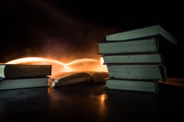 Bir yığın eski kitap. Ahşap masanın üzerinde antika bir kitap. Karanlıkta parlayan bir kitabın etrafında sihirli bir yıldırım. Seçici odak