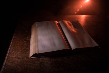 Bir yığın eski kitap. Ahşap masanın üzerinde antika bir kitap. Karanlıkta parlayan bir kitabın etrafında sihirli bir yıldırım. Seçici odak