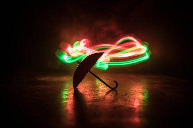 Masanın üzerinde koyu tonlu sisli minyatür bir şemsiye silueti var. Yaratıcı bir kavram. Seçici odak