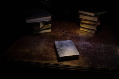 Bir yığın eski kitap. Ahşap masanın üzerinde antika bir kitap. Karanlıkta parlayan bir kitabın etrafında sihirli bir yıldırım. Seçici odak